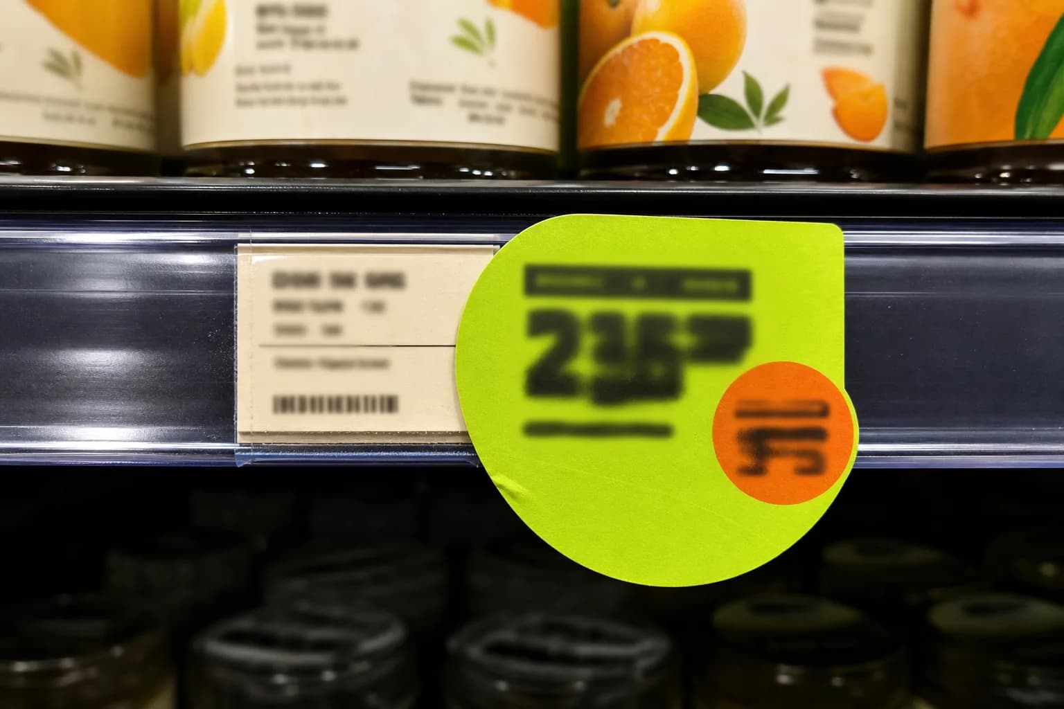 מדבקת מבצע ירוקה על מדף בסופרמרקט ליד תווית מחיר ליחידה